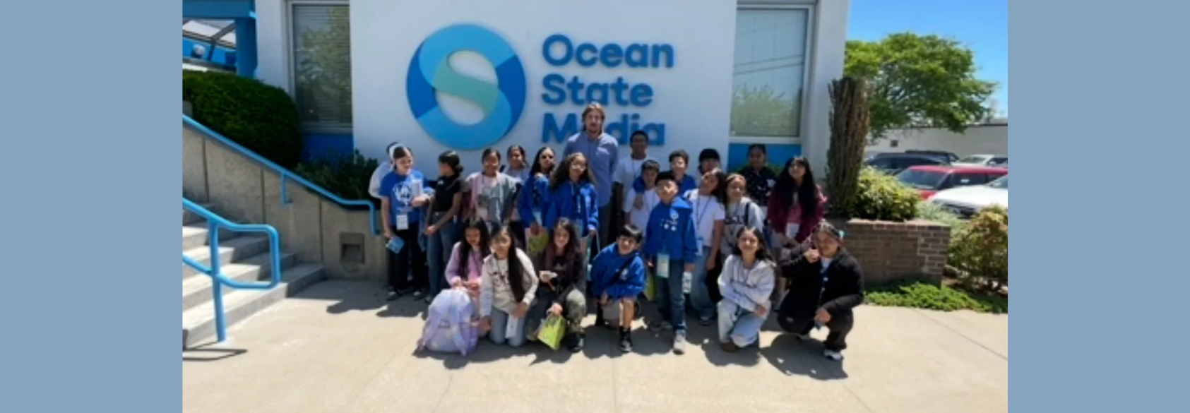 Ocean stagte media sign with students posed in front of it